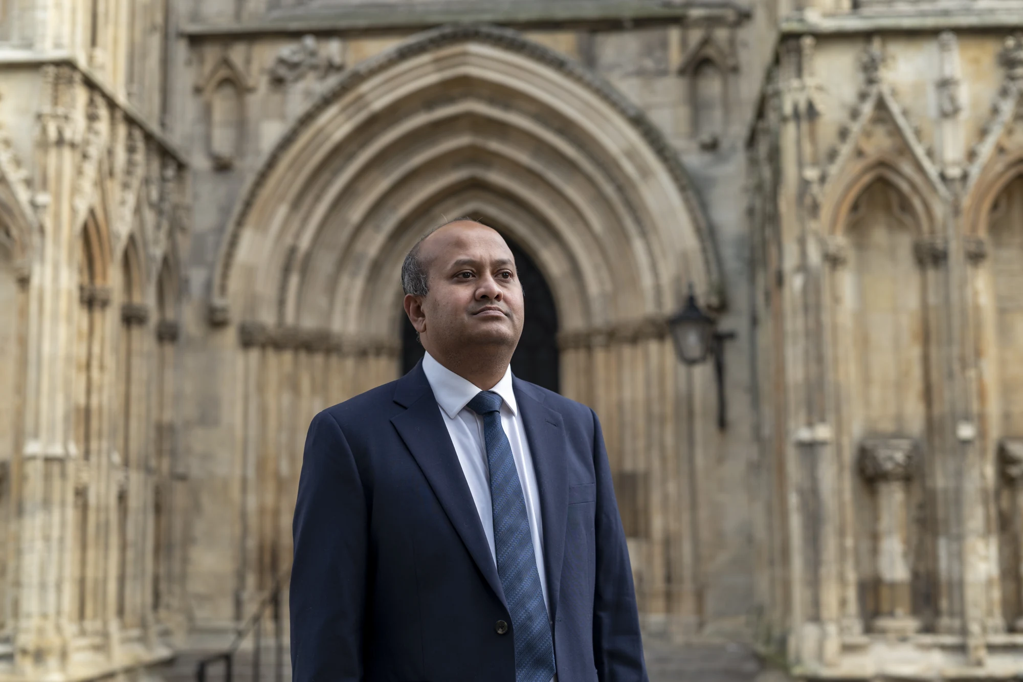 Portrait of William Gomes in front of carved stonework